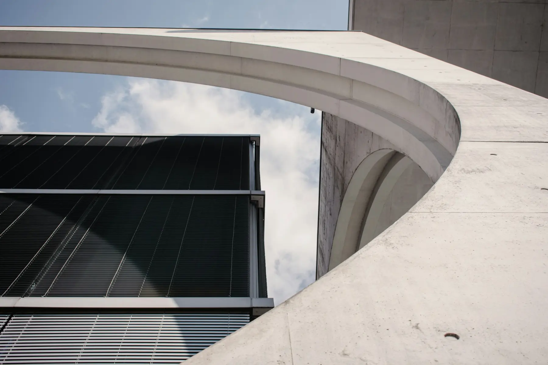 Gerundete Betonarchitektur mit Glasfassade, kühles Licht